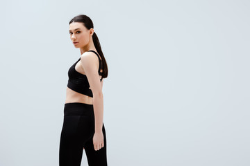 Wall Mural - beautiful woman in black sportswear standing isolated on white