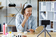 © YURII MASLAK - Young female blogger recording a tutorial video for her beauty blog about cosmetics.Vlogger testing face cream and broadcast live video to social network at home.Blogging, videoblog, skincare concept.
