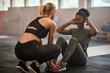 © Flamingo Images - Young woman doing sit-ups in a gym with a partner
