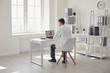 © Studio Romantic - Doctor online. Male doctor works talking video call with patient using bast shoe while sitting at desk in back view clinic office.
