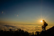 photographer stand at the top of the mountain, under the sunset and he is higher than the sun