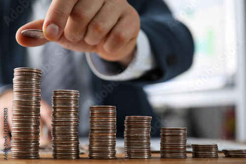 Fotografía Male hands in suit stack coins on table, saving
