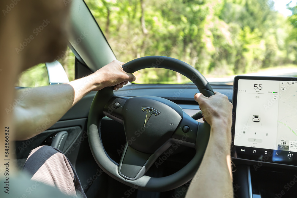 Person driving a new Tesla Model 3 Stock Photo | Adobe Stock