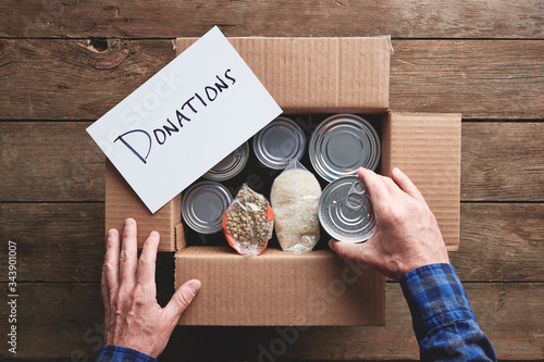 Cuadros en Lienzo a person packing a donation box with food items