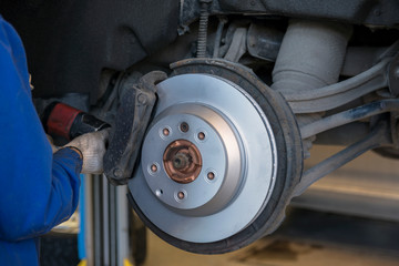 Wall Mural - Car repair in a car service. Replacing brakes in a car service. New brake disc close up.