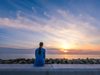 Wall Mural - Silhouette of a woman in the blue shirt on the pink sunset background