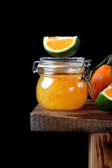 Wall Mural - Citrus jam of kumquats and two sorts of mandarins with thyme and anise in a glass jar on the edge of the wooden table