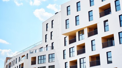 Contemporary residential building exterior in the daylight. Modern apartment buildings on a sunny day with a blue sky. Facade of a modern apartment building