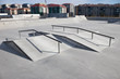 Sloped metal rails for grind tricks in an empty concrete skatepark