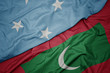 waving colorful flag of maldives and national flag of Federated States of Micronesia .