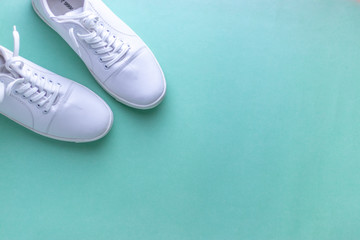 White sneakers on light blue colour background, flat lay top view minimal background. 
