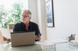 © Tetra Images - Senior man sitting in home office and using laptop