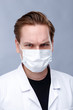 © Roman - Doctor in a mask in a white coat on a gray background
