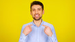 © viacheslav - Choose me! Handsome bearded man shows his fingers on a yellow background with copyspace. Guy in a light blue shirt with his hands up. Place for text or product