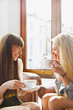 © fStop - Happy young women drinking coffee in cafe window