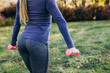© Cavan Images - Closeup of buttocks girl holding dumbbells in fitness gym in park.
