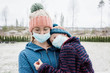 © Cavan Images - mother carrying son with face masks on for protection from virus & flu