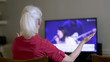 An older woman worshiping as she attends church virtually by streaming the online platform to her television because congregation and group fellowship is restricted during COVID19 pandemic.