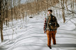 © Cavan Images - man with canvas pack hikes through deep snow in the Maine woods