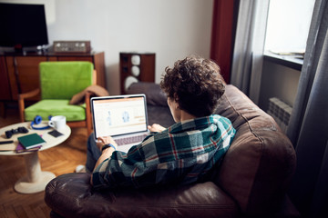 Wall Mural - Curly-haired guy using modern laptop at home