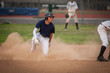© Cavan Images - Young baseball player in cloud of dust after sliding into second base