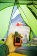 © Cavan Images - Man holds GPS and satellite safety communication device in tent.