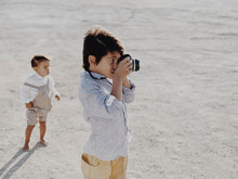 Boy Taking Picture With Vintage Camera With Kid Standing In Background