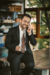 © Svyatoslav Lypynskyy - Cheerful Happy Businessman Talks With Mobile Phone Sitting On Desk