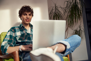 joyful young man using modern notebook at home