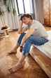 © Yakobchuk Olena - Attractive young man sitting on bed at home