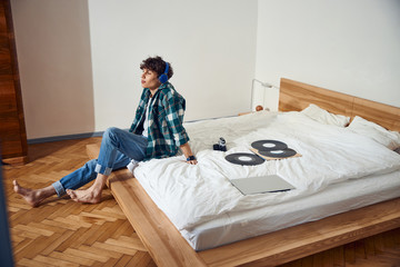 Wall Mural - Smiling handsome guy listening to music at home