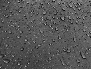 Drops of water on a black metal surface, beautiful background after rain