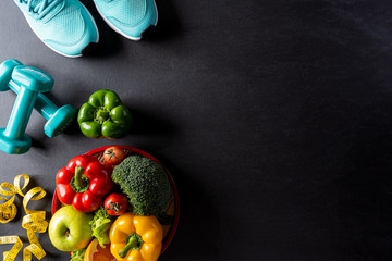 World health day, Healthcare and medical concept. Healthy food including fresh fruits, vegetables, sports shoes, dumbells and measure tape on black background.