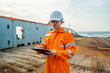 © Igor Kardasov - Filipino deck Officer on deck of offshore vessel or ship , wearing PPE personal protective equipment. He fills checklist. Paperwork at sea