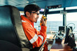 © Igor Kardasov - Filipino deck Officer on bridge of vessel or ship wearing coverall during navigaton watch at sea . He is speaking on portable GMDSS VHF radio, short range communication