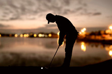 Silhouette Man Playing Golf At Sunset