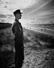 Side View Of Army Soldier Standing At Beach Against Sky