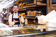 © JackF - Male shop assistant demonstrating delicious loaves of bread in bakery