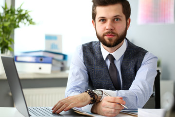 Handsome smiling bearded clerk man at office workplace with silver pen in arms do paperwork portrait. Staff dress code worker job offer client visit study profession boss stock idea coach training