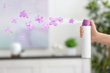 Woman Spraying Floral Air Freshener At Home
