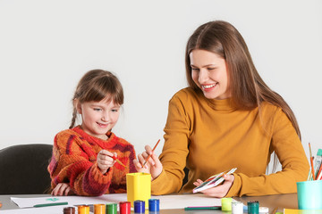 Wall Mural - Drawing teacher giving private art lessons to little girl on light background