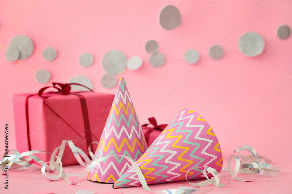 Party hats, gift and decor on color background