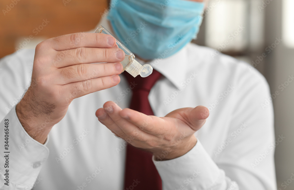 Businessman with disinfectant in office, closeup