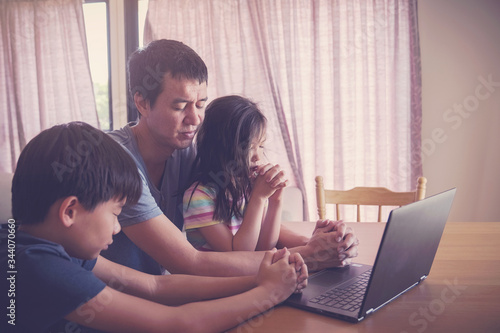 Children praying with father parent with laptop, family and kids worship online together at home, streaming online church service, social distancing, new normal  concept