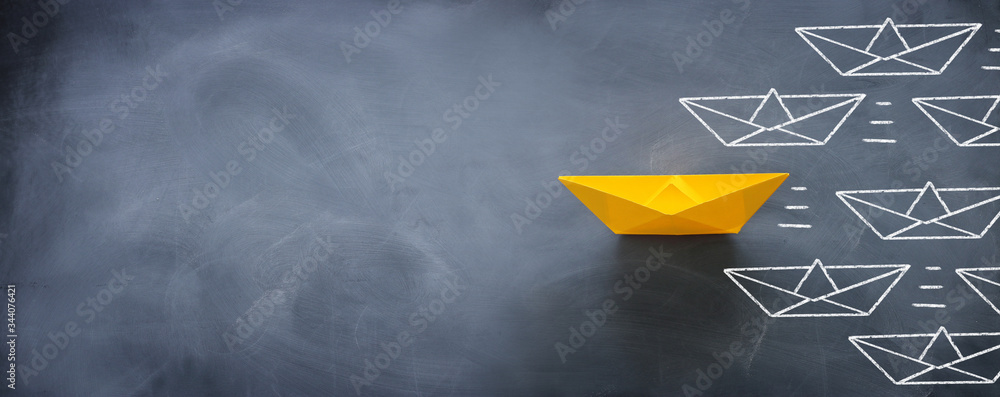 Leadership banner concept with paper boat on blackboard background. One leader ship leads other ships. - obrazy, fototapety, plakaty 