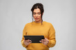 technology and people concept - serious woman using tablet computer over grey background