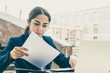 © Mangostar - Businesswoman with laptop and documents in cafe. Foused young businesswoman working with papers and laptop computer while sitting in outdoor cafe. Business concept