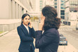 © Mangostar - Businesswomen talking by smartphones on street. Two serious female colleagues in formal wear standing on urban city street and talking by cell phones. Communication concept
