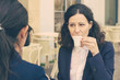 © Mangostar - Business colleagues drinking coffee in outdoor cafe. Professional female coworkers in formal wear sitting at table and drinking coffee together. Coffee time concept