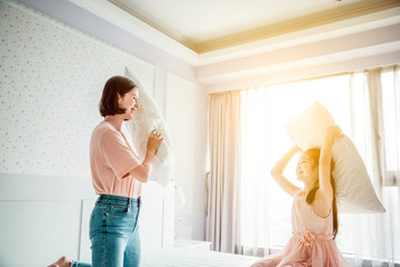 Wall Mural -  happy mother and daughter playing on the bed in the bedroom